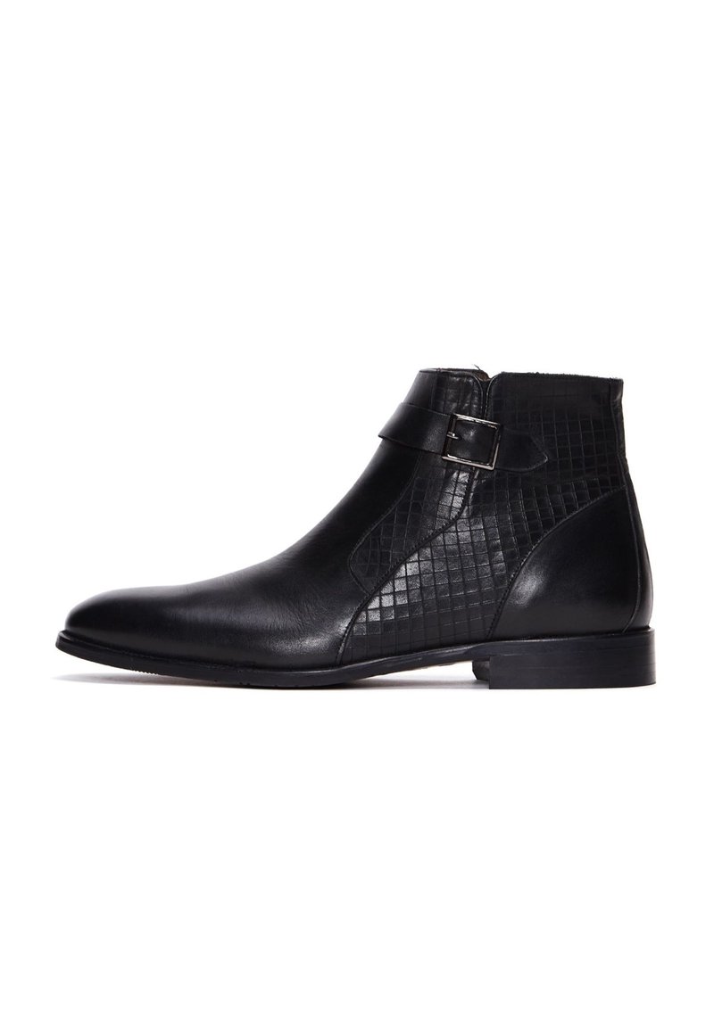 Botines negros con piel suave, un diseño de rejilla texturizada en el costado, una correa con hebilla y un tacón bajo apilado.