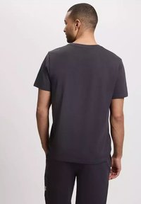 Męska koszulka polo z krótkim rękawem w ciemnoszarym kolorze, z okrągłym dekoltem i gładką fakturą. Prosty design bez widocznych wzorów czy ozdób.