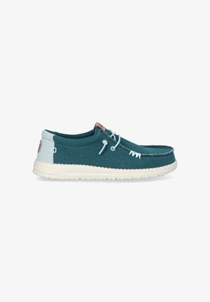 Scarpa casual azzurro petrolio e azzurro chiaro senza lacci con suola bianca, lacci decorativi e dettagli cuciti lungo la punta e i lati.