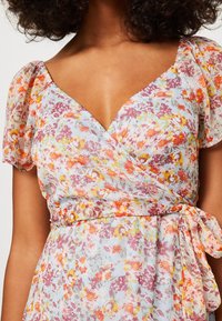 Abito a portafoglio floreale con maniche a sbuffo corte. Tessuto leggero e trasparente con un motivo floreale multicolore nelle tonalità di rosa, arancione e giallo. Dettaglio con fiocco in vita.