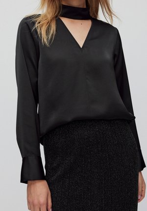 Blusa nera in raso con scollatura a V, maniche lunghe e dettaglio choker. Texture liscia, design minimalista, ideale per abbigliamento formale o casual.