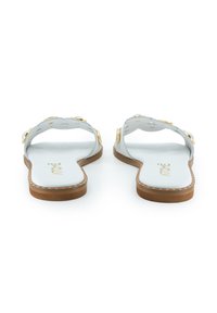Graue Flip-Flops mit flachem Design und goldfarbenen, runden Akzenten, ausgestattet mit einer glatten Oberfläche und einer braunen Sohle. Weißes Innenetikett sichtbar.