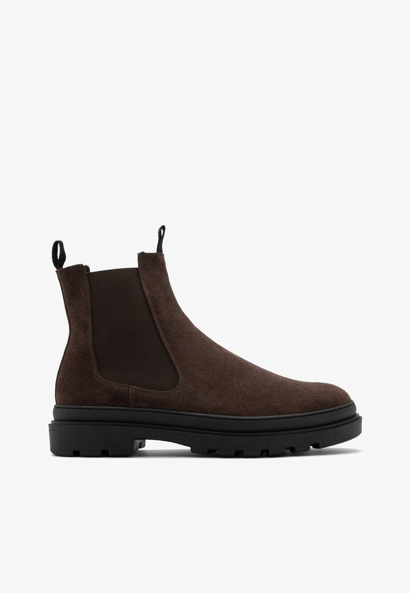 Brązowe zamszowe botki Chelsea z elastycznymi bocznymi panelami i pętelkami, z masywną czarną gumową podeszwą z fakturą.