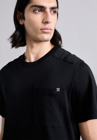 T-shirt in cotone nero con maniche corte, spalline e tasca sul petto con un piccolo etichetta logo. Tessuto morbido e strutturato.