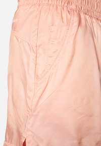 Světlé broskvové kraťasy vyrobené z texturované látky. Mají elastický pas a boční kapsu s nenápadnými švy.