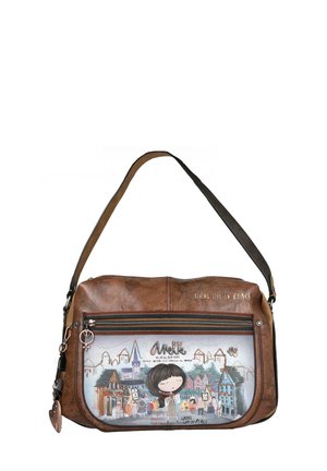 Bolso de imitación de cuero marrón con una correa de hombro negra, que presenta un bolsillo frontal ilustrado que representa una escena de pueblo y acentos de texto.