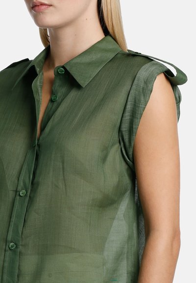 Sheer green button-up shirt with a collar and cap sleeves, featuring textured fabric and green buttons on the front.