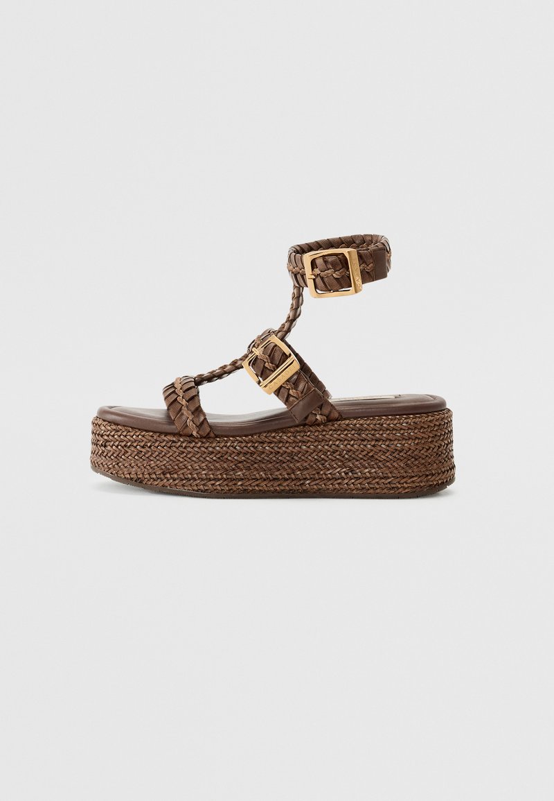 Sandale plateforme împletite maro, cu o talpă groasă din jute împletit, având o închidere cu două catarame și curele împletite.