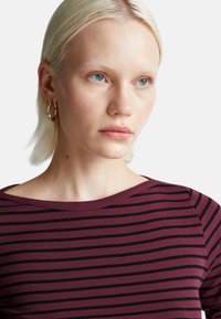 Górna część w kolorze burgundowym i czarnym w poziome paski z okrągłym dekoltem. Gładki, miękki materiał w luźnym kroju. Charakteryzuje się wyraźnym wzorem w poziome paski.