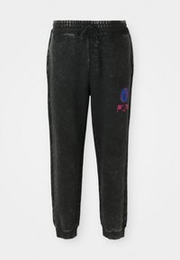 Sorte joggebukser med en teksturert overflate, med snøring i livet, side-striper og et fargerikt grafisk motiv på venstre lår.