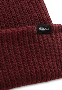 Punainen neulottu pipo, jossa on ribbikuvio ja taitettu reunus, etuosassa pieni musta Vans-logo-otsikkotagi ommeltuna.