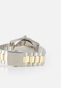 Armbands i rostfritt stål i silver- och guldton med en polerad finish. Har ett säkert spänne och länkar som växlar i färg.