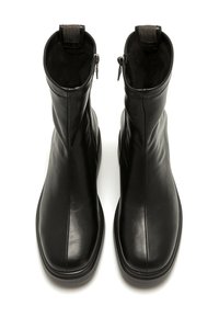 Botas de tobillo negras de cuero suave con cremallera a cada lado y una lengüeta texturizada, con puntera redonda y suela plana.