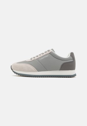 Sneakers Calvin Klein in suede grigio e grigio chiaro con una parte superiore in sintetico liscio, design con lacci e suola in gomma testurizzata.