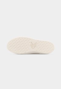 Semelle de chaussure en caoutchouc blanc avec un motif en tissage de panier et un logo "CK" embossé au centre sur un fond uni.