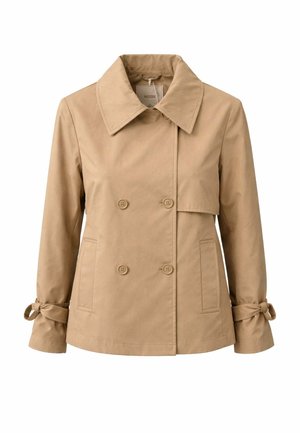 Giacca doppiopetto beige con ampio colletto, chiusura con bottoni, tasche e polsini annodati sulle maniche lunghe su sfondo bianco.