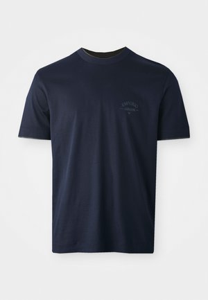 Camiseta de algodón azul marino con mangas cortas, cuello redondo y un logo bordado en el lado izquierdo del pecho. Textura suave, ajuste clásico.