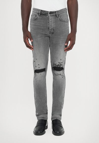 Jeans de denim gris con detalles desgastados en las rodillas y sutiles acentos gráficos. Presenta un diseño clásico de cinco bolsillos y una silueta ajustada.