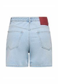 Short en jean bleu clair avec deux poches arrière et un patch de marque en cuir marron sur la ceinture.