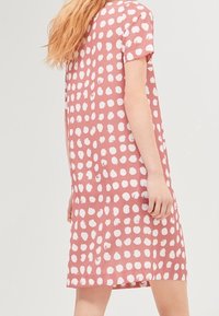 Vestido corto rosa con corte holgado, que presenta grandes lunares blancos, mangas cortas y una textura suave.