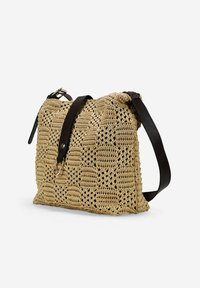 Bolso de croché tejido en beis con una superficie texturada, con una correa de cuero marrón oscuro y herrajes metálicos, estructurado en forma rectangular.