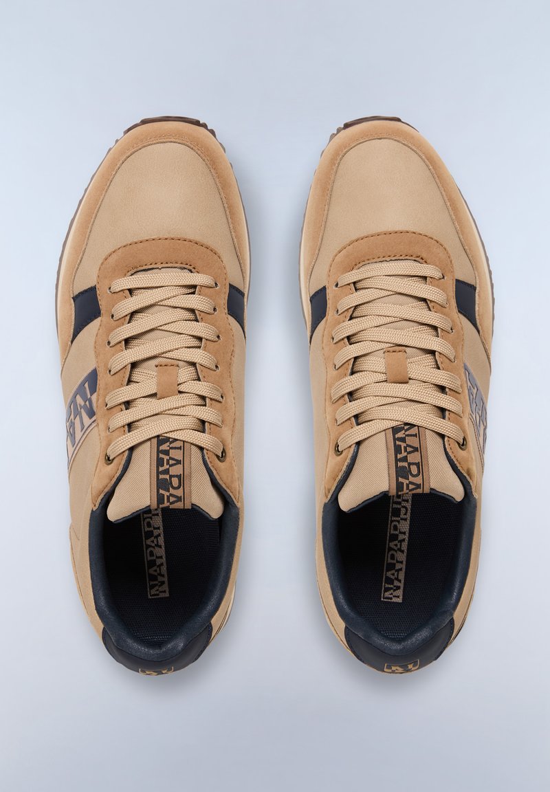 Zapatillas beige hechas de materiales de ante y malla, con acentos en azul oscuro, cordones redondos y una suela de goma texturizada. Logo en el lateral.