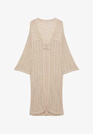 Cárdigan beige de punto abierto con mangas anchas y acampanadas, lazo decorativo en el frente y bordes con volantes. Presenta un patrón similar al encaje en toda su superficie.