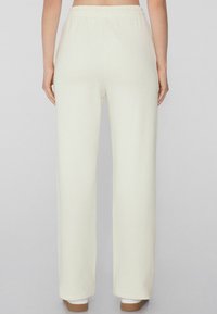 Crème-kleurige wijde broek gemaakt van zachte stof met een elastische tailleband, met een glad, minimalistisch ontwerp en zonder zichtbare zakken.