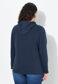Navy sweatshirt met een capuchon, lange mouwen en een ontspannen pasvorm. Zachte stof en een eenvoudig ontwerp zonder zichtbare patronen of accenten.
