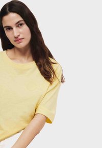 Geel katoenen t-shirt met een ontspannen pasvorm. Korte mouwen en een ronde hals. Gladde textuur, minimalistisch ontwerp, zonder zichtbare patronen of accenten.