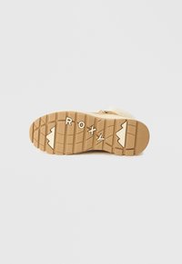 Σόλα μπότας σε ανοιχτό καφέ χρώμα με υφή και μοτίβο γραψημένο, που φέρει τη λέξη "ROXY" σε λευκό. Καουτσούκ υλικό με ανυψωμένα σχέδια για καλύτερη πρόσφυση.