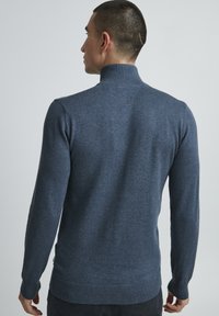 Maglione azzurro a maglia con colletto alto, texture liscia e polsini a coste. Design aderente, senza motivi o dettagli visibili.