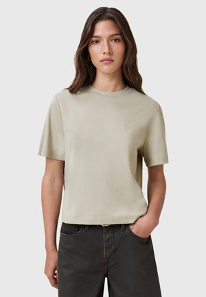 Ljusbeige kortärmad t-shirt med rund halsringning och en subtil broderad solgrafik på bröstet. Mjuk bomullstextur.