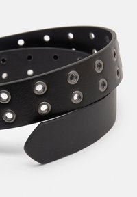 Cintura in pelle nera caratterizzata da ritagli circolari, rinforzata con rivetti in metallo e una finitura liscia sull'estremità affusolata.