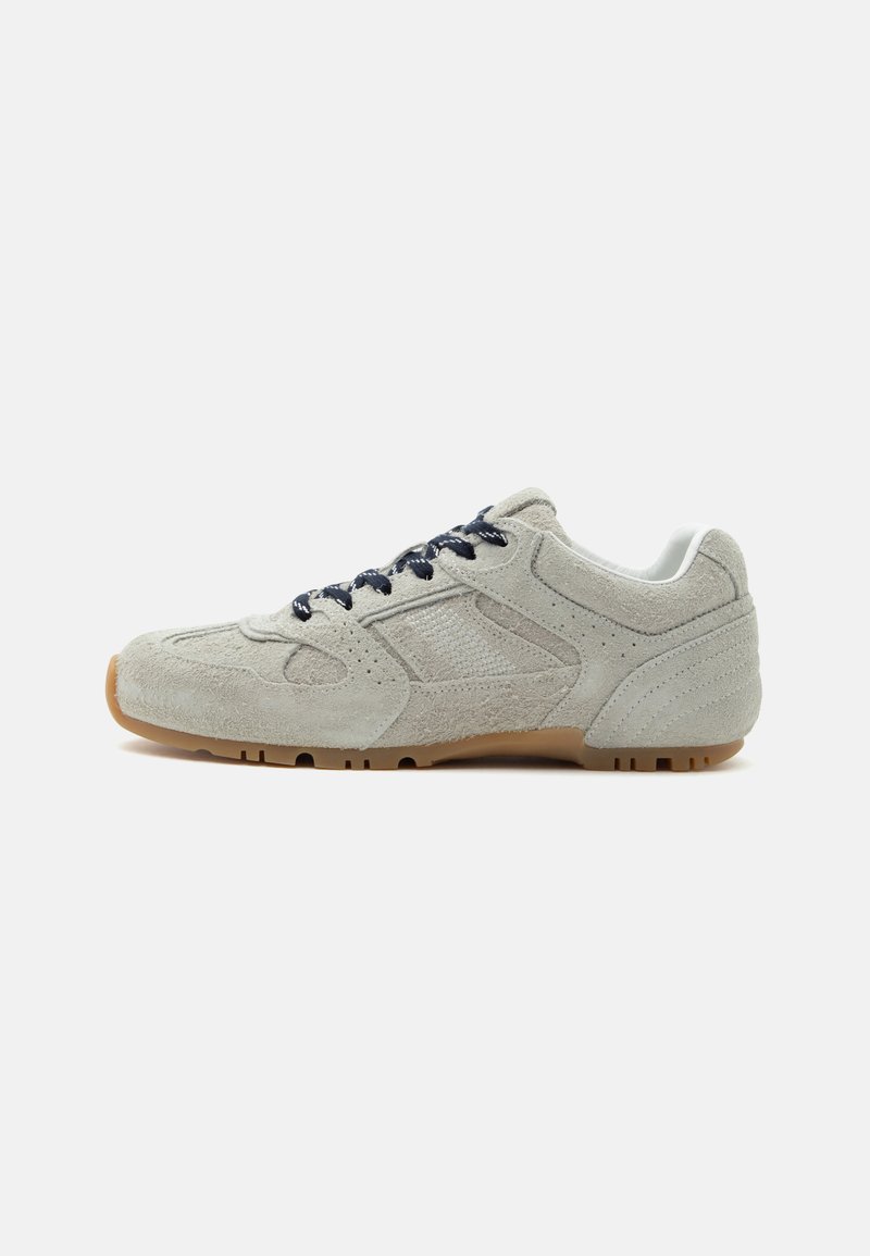 Baskets en daim gris clair avec des lacets bleu foncé et une semelle en caoutchouc gomme, vues de côté sur fond blanc.