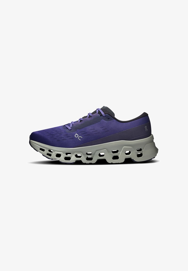 Chaussure de sport violette et noire avec semelle grise, dotée de larges trous de ventilation et d'un design à lacets, vue de côté sur fond blanc.