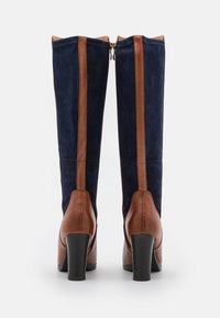 Knee-high boots featuring a navy suede upper with brown leather accents and a block heel, zipper closure at the back for easy wear.