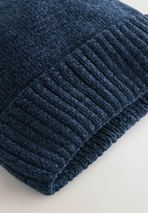 Marinblå stickad mössa med en texturerad, ribbad kant och slät kropp, tillverkad av en mjuk ullblandning för värme och komfort.