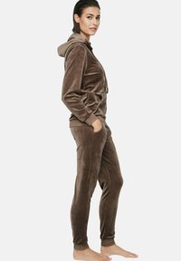 Ensemble de survêtement en velours marron avec capuche, comprenant des manches longues et un pantalon ajusté. Texture douce et poignets élastiques, conçu pour le confort.