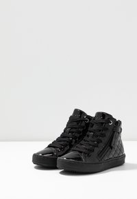 Svarta hög-top sneakers med en glossy lackfinish, som har en quiltad textur, framsnörning och sidozipper för enkel stängning.