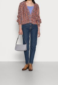 Värgglad, texturerad kardiagan med vida ärmar över en ljuslila topp, ihop med blå jeans och bruna ankelstövlar. En grå handväska ingår.