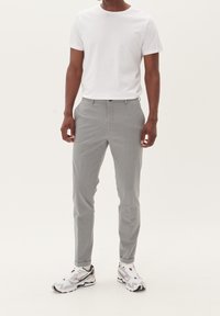 Grå skräddarsydda byxor med smal passform, med slät front, sidofickor och ankellängd. Kombineras med en enkel vit t-shirt och sneakers.