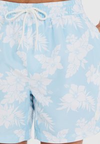 Blå badshorts med ett vitt blommönster, elastisk midja och dragsko fram, tillverkade av ett lätt tyg.