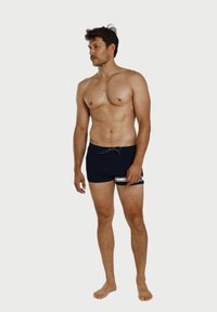 Dunkelblaue Badeshorts mit einem Bindegürtel, die ein weißes horizontales Streifenmuster am Saum aufweisen. Hergestellt aus elastischem Material.