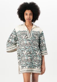 Cămașă cu mânecă scurtă și guler, având un model floral în nuanțe de teal și maro pe un fundal crem, cu garnituri decorative și slituri laterale.