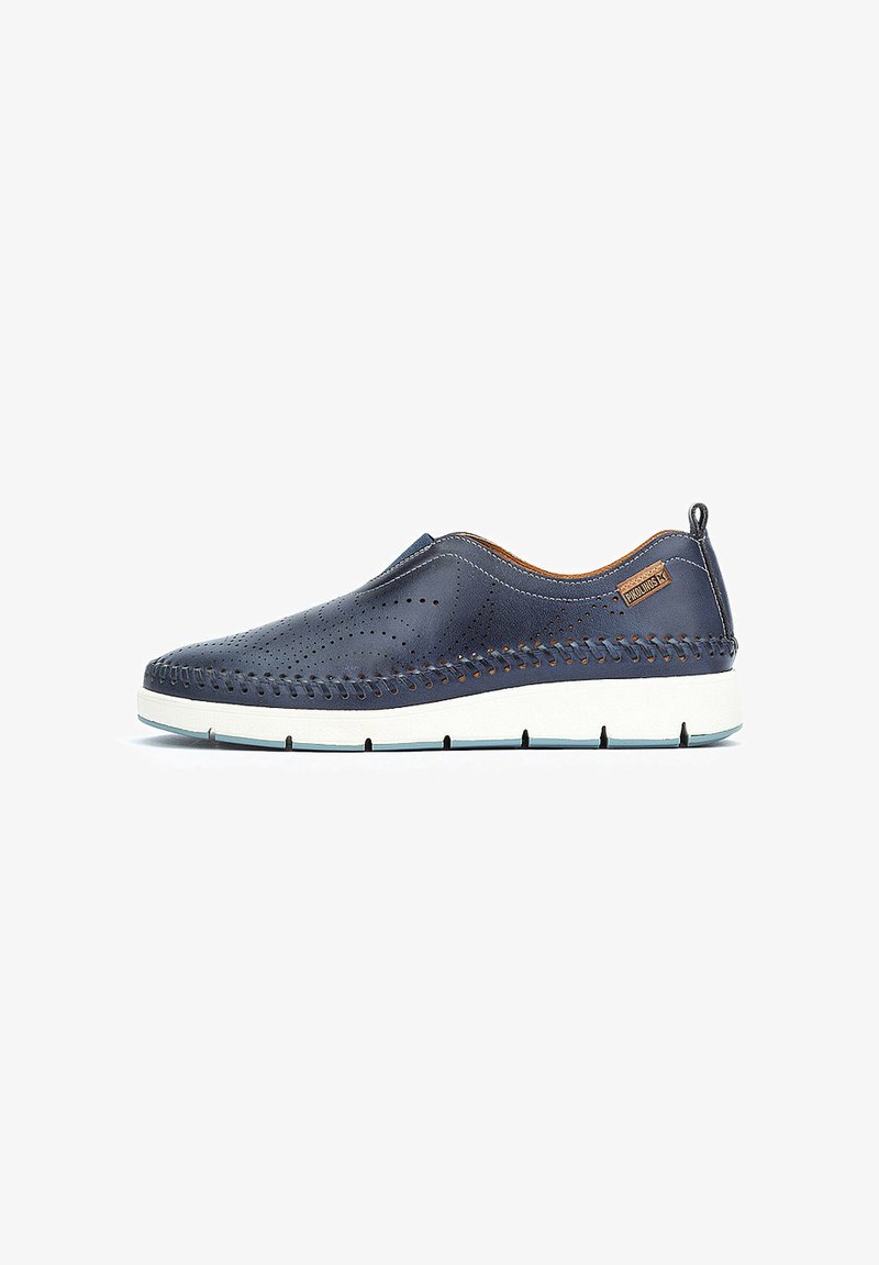 Chaussures en cuir bleu marine à enfiler avec un design perforé, accents beiges et semelle en caoutchouc blanche. Dotées de coutures décoratives le long des bords.