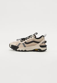 Ljusbeige vandringsskor med svarta detaljer, strukturerat mönster, elastiskt snörsystem och Vibram-sula för bra grepp. Gummibeklätt häl och logotypdetalj.