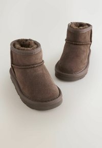 Pruunid sametiste ankle kingad pehme vale karvaga voodriga, ümar kuju, paksud kummitaldad ja dekoratiivne õmblus õmbluste ääres.