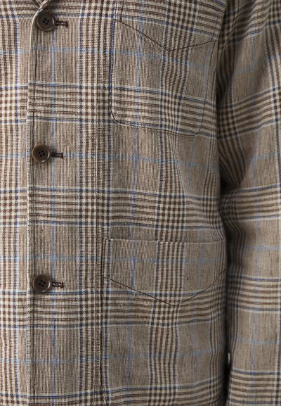 Brown and blue plaid patterned shirt with a button-down front, two chest pockets, and a textured fabric. Features brown button accents.