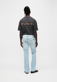 Σκούρο γκρι βαμβακερό μπλουζάκι με γραφικό "ALLSAINTS", σε συνδυασμό με ανοιχτό μπλε τζιν τζιν με διακριτικές ραφές και πίσω τσέπες.